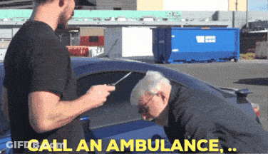 Man In Black Shirt Talking To Older Man In Blue Car Saying Call An Ambulance GIF