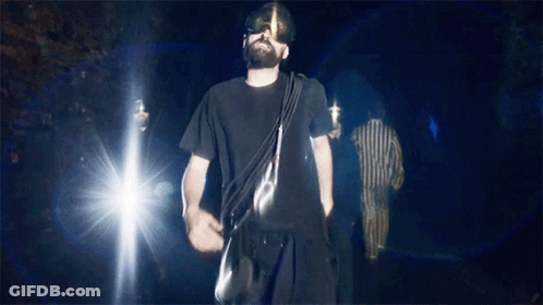 Man In Black Shirt Walking Dark With Bag GIF