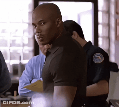 Man In Black Shirt With Blue Badge GIF