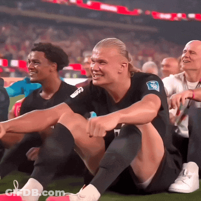 Man In Black Shirt With NN Sitting On Ground GIF