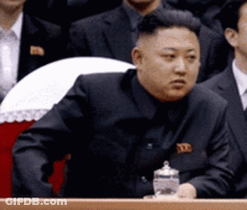 Man In Black Suit At Podium With Water GIF