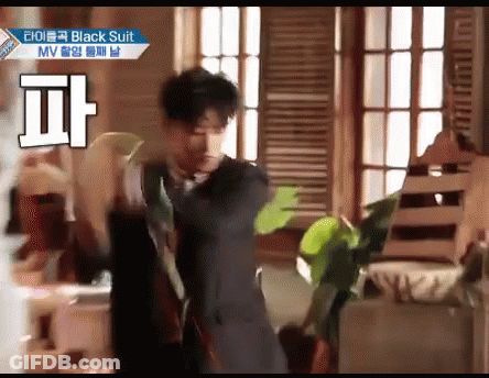 Man In Black Suit Dancing In Room With Plant GIF