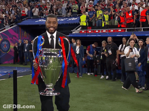 Man In Black Suit Holding Trophy In Front Of Crowd GIF