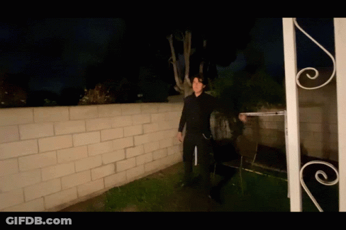 Man In Black Suit In Front Of Brick Wall GIF