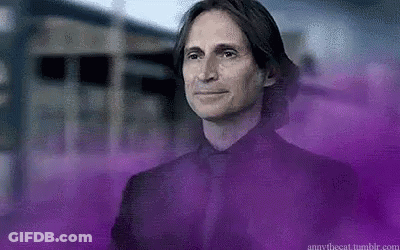 Man In Black Suit In Front Of Building With Purple Smoke GIF