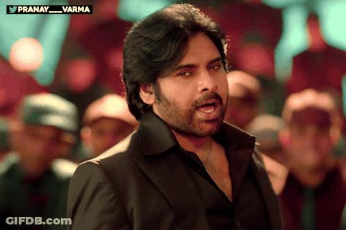 Man In Black Suit In Front Of Crowd With Pranay Varma Above GIF