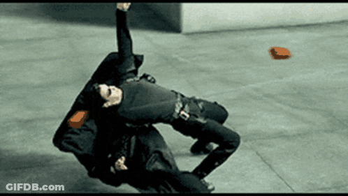 Man In Black Suit Laying On Ground With Red Object GIF