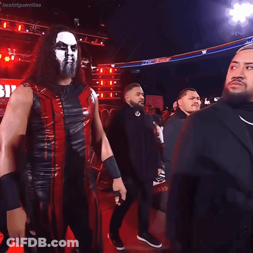 Man In Black Suit Next To Man In Red Jacket GIF