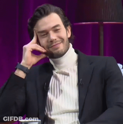Man In Black Suit Smiling With Hand On Face GIF