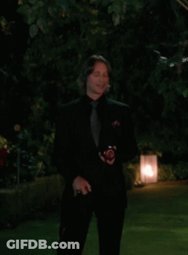 Man In Black Suit Standing In Dark Garden GIF