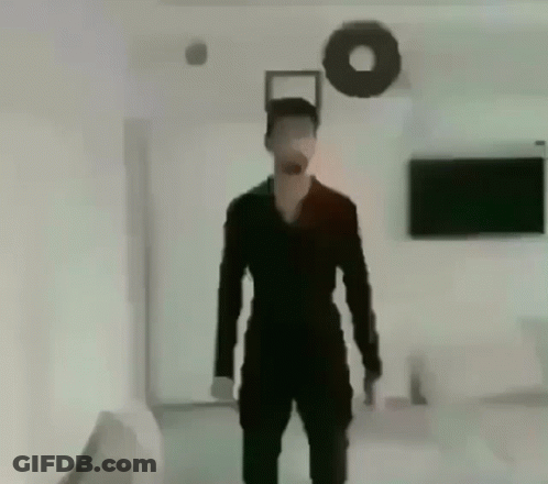 Man In Black Suit Standing In Living Room With Wreath GIF