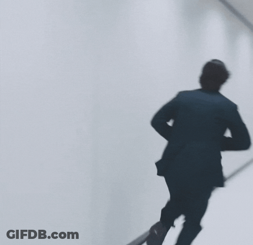 Man In Black Suit Walking Down Hallway GIF