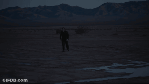 Man In Black Suit Walking In Desert GIF