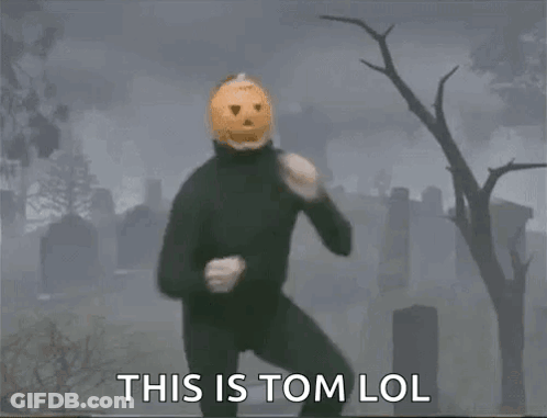 Man In Black Suit With Pumpkin Head In Cemetery GIF