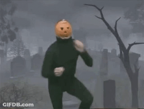Man In Black Suit With Pumpkin Head In Cemetery GIF