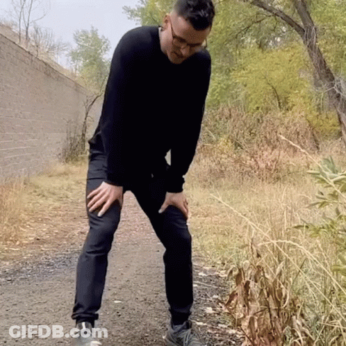 Man In Black Sweater Holding Knee In Pain GIF