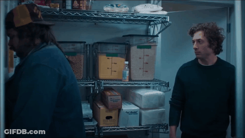 Man In Black Sweater Next To Man In Yellow Hat GIF