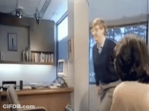 Man In Black Sweater Next To Woman In Office GIF
