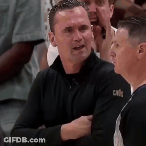 Man In Black Sweater With Cavs Sleeve Talking To Another Man GIF