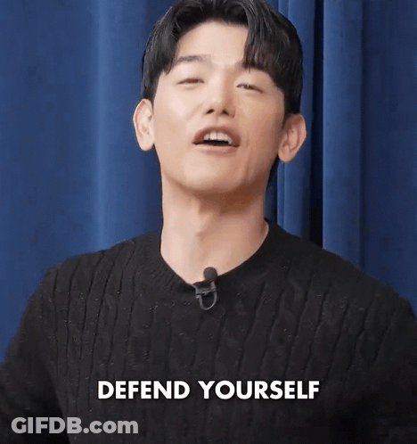 Man In Black Sweater With Microphone Says Defend Yourself GIF