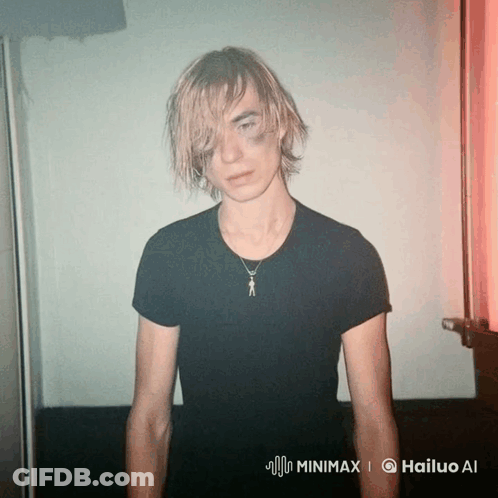 Man In Black T-Shirt And Necklace Standing In Red Light GIF
