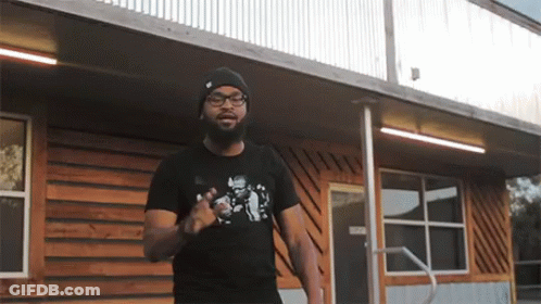 Man In Black T-Shirt With Skull Standing In Front Of Building GIF