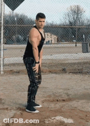 Man In Black Tank Top And Camo Pants At Chain Link Fence GIF