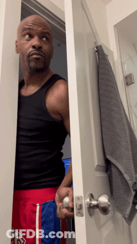 Man In Black Tank Top And Red Shorts In Bathroom GIF