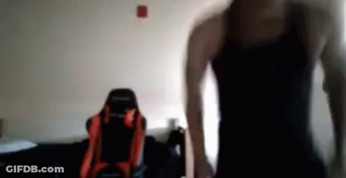 Man In Black Tank Top In Front Of Red And Black Chair GIF