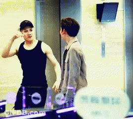 Man In Black Tank Top Talking To Man In Grey Jacket GIF