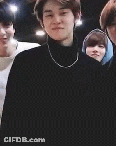 Man In Black Turtleneck And Necklace Standing Before Group GIF