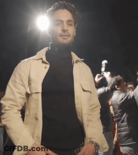 Man In Black Turtleneck And White Jacket In Crowd GIF