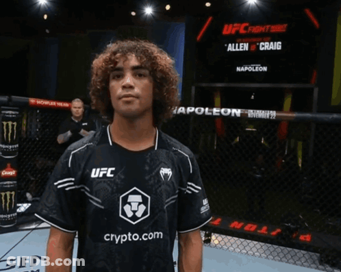 Man In Black UFC Shirt In Front Of Poleon Screen GIF