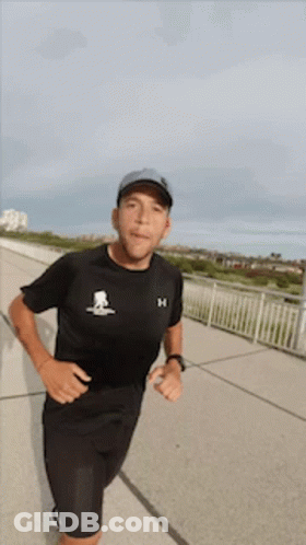 Man In Black Under Armour Shirt Running On Sidewalk GIF