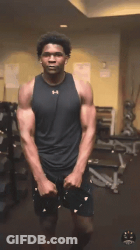 Man In Black Under Armour Tank Stretches GIF
