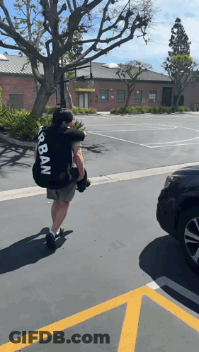 Man In Black Urban Shirt Carrying Large Bag GIF