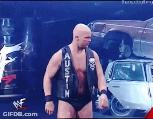 Man In Black Vest Saying Austin In Front Of Pile Of Cars GIF