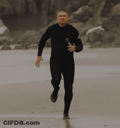 Man In Black Wetsuit Running On Beach GIF
