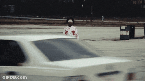 Man In Bloody Shirt Standing In Front Of Car GIF