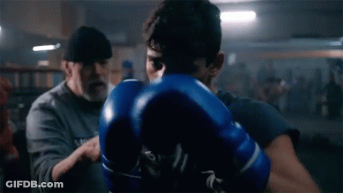 Man In Blue Boxing Gloves Being Instructed In Gym GIF
