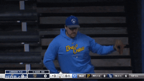Man In Blue Brew Crew Sweatshirt In Front Of Scoreboard GIF