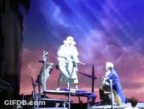Man In Blue Coat Standing On Stage With Sword GIF
