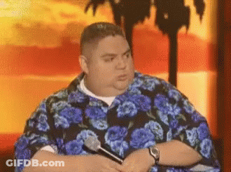 Man In Blue Floral Shirt Holding Microphone In Front Of Palm Tree GIF