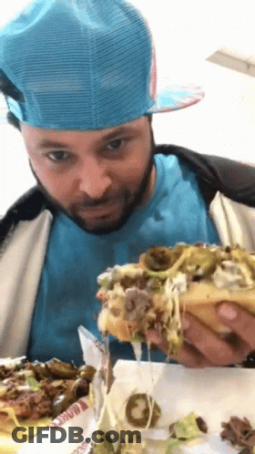 Man In Blue Hat And Blue Shirt Eating Hamburger GIF