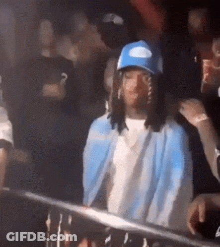 Man In Blue Hat And Jacket Standing In Crowd GIF
