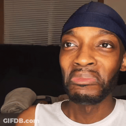 Man In Blue Hat And White Tank Top Looking At Camera GIF