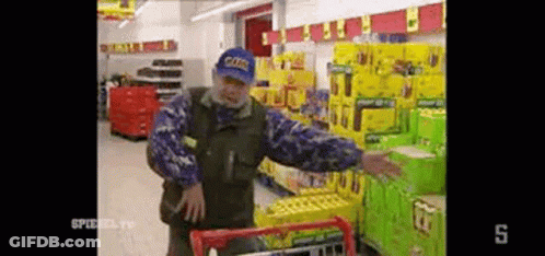 Man In Blue Hat Pushing Shopping Cart GIF