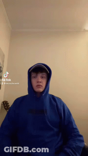 Man In Blue Hoodie And Hat Sitting By Guitar GIF