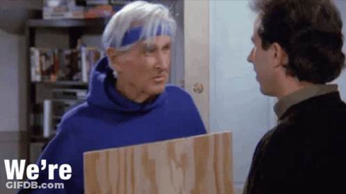 Man In Blue Hoodie Holding Board Talking To Another Man GIF