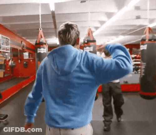 Man In Blue Hoodie In Gym With Everlast Punching Bags GIF